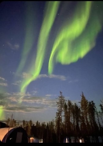 Aurora borealis in a clear night sky over a camp