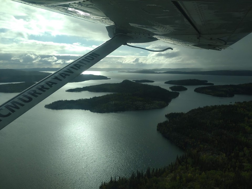 Islands in a lake with storm clouds in the background. Image is taken from an aircraft and has the wing and strut in the foreground